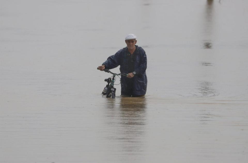 A man with a bicycle walks in a flooded street after the passage of hurricane Fiona, in Toa Baja, Puerto Rico (EPA)