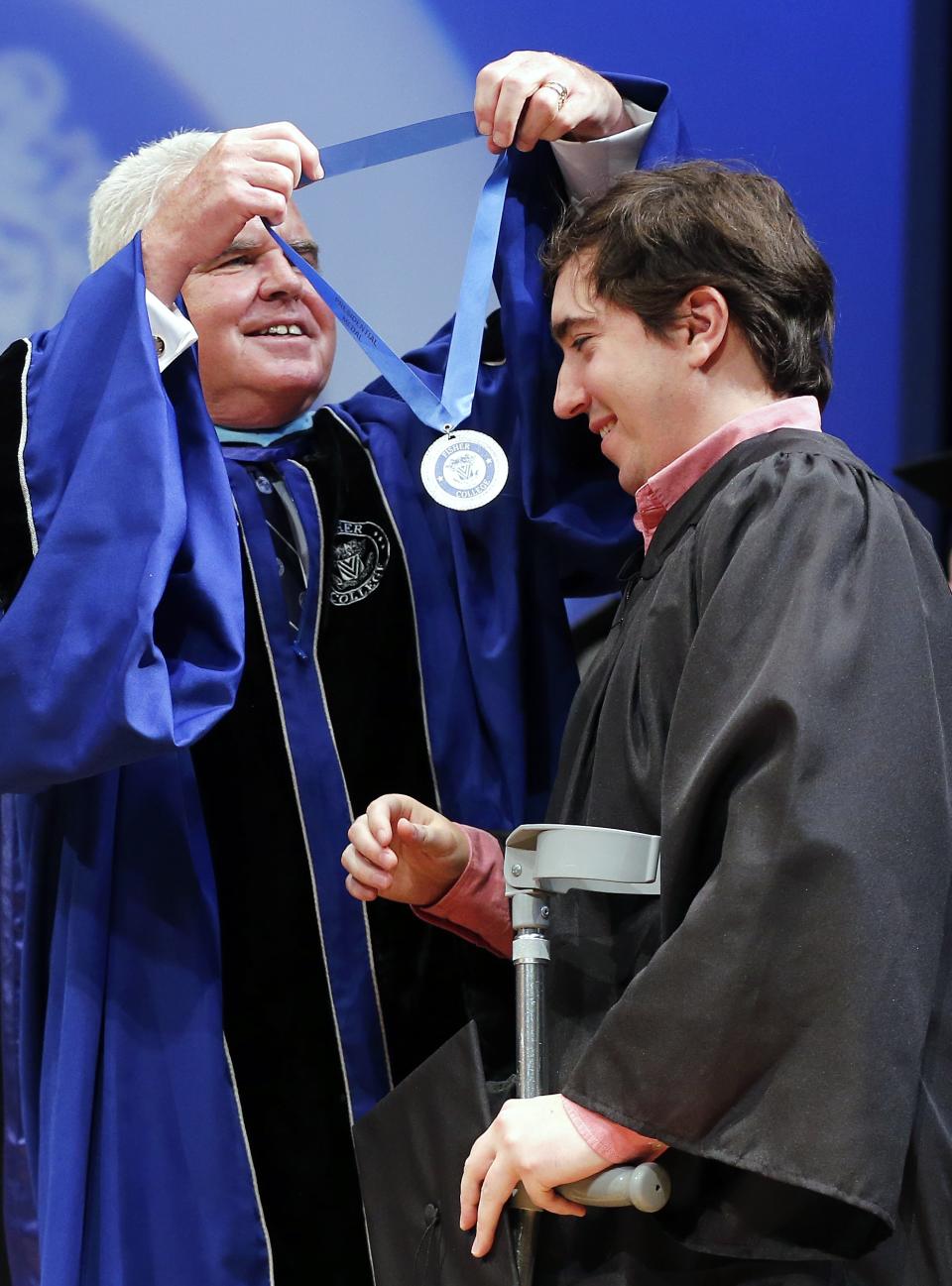 Boston Marathon bombing survivor Jeff Bauman, right, receives a medal from the president of Fisher College Dr. Thomas McGovern during commencement ceremonies in Boston, Saturday, May 10, 2014. Bauman lost his legs in the attack. Bauman and Carlos Arrendondo, who saved Bauman's life the day of the bombing, each gave graduation speeches and were awarded honorary degrees during the ceremony. (AP Photo/Michael Dwyer)