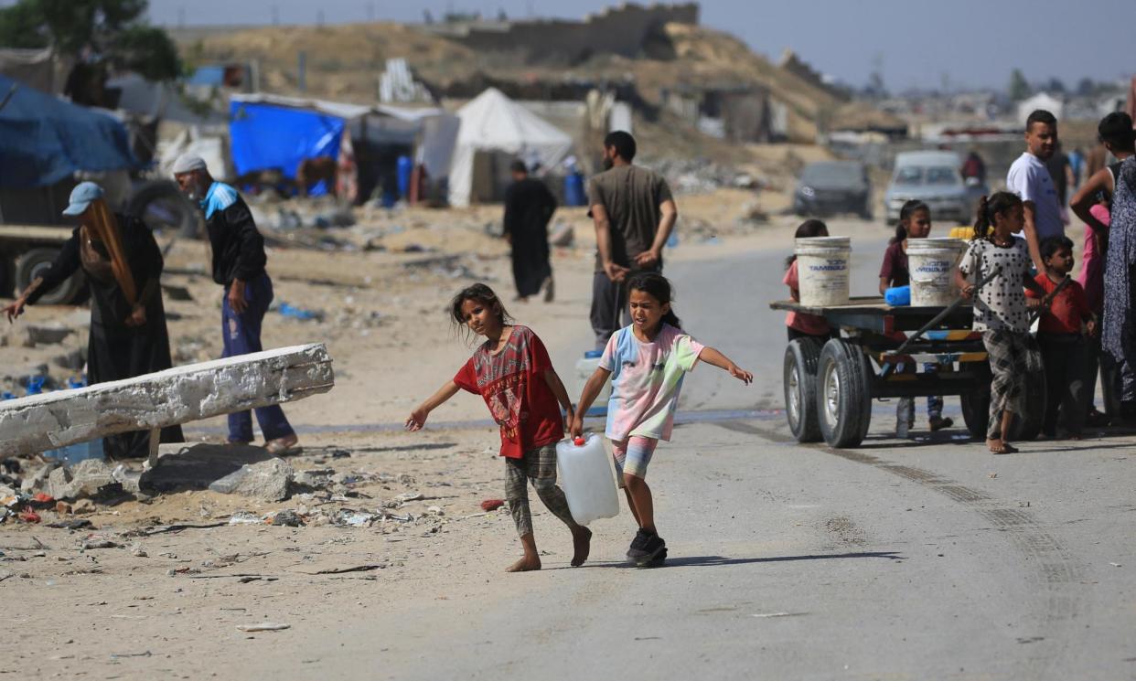 <span>Displaced Palestinian children carry water in a makeshift camp in Khan Yunis on the Gaza Strip, May 2024.</span><span>Photograph: Eyad Baba/AFP/Getty Images</span>