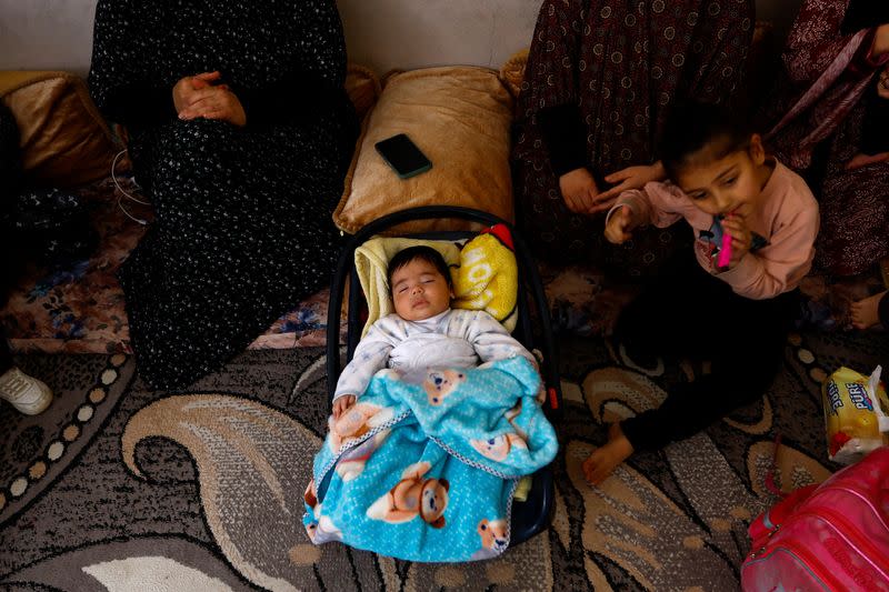 Members of Palestinian, Basheer's family sit in their relatives' house after the destruction of their house in Israeli air strikes, in Deir al-Balah town