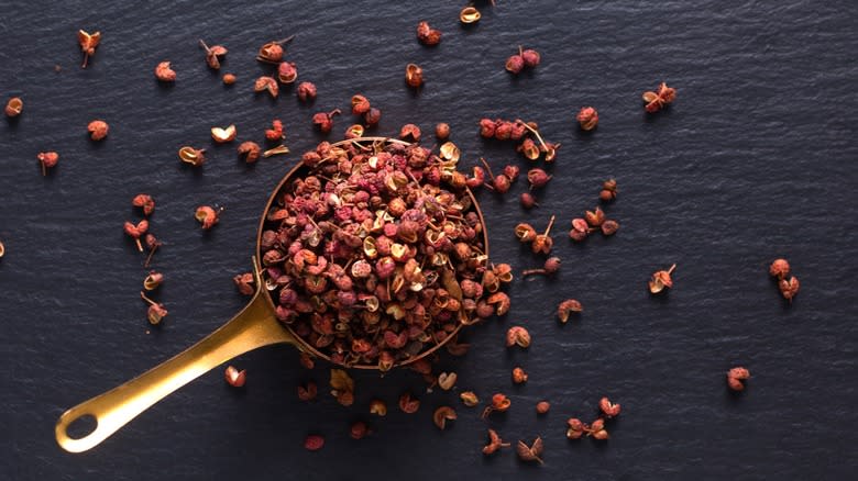 Sichuan peppercorns in brass measuing cup