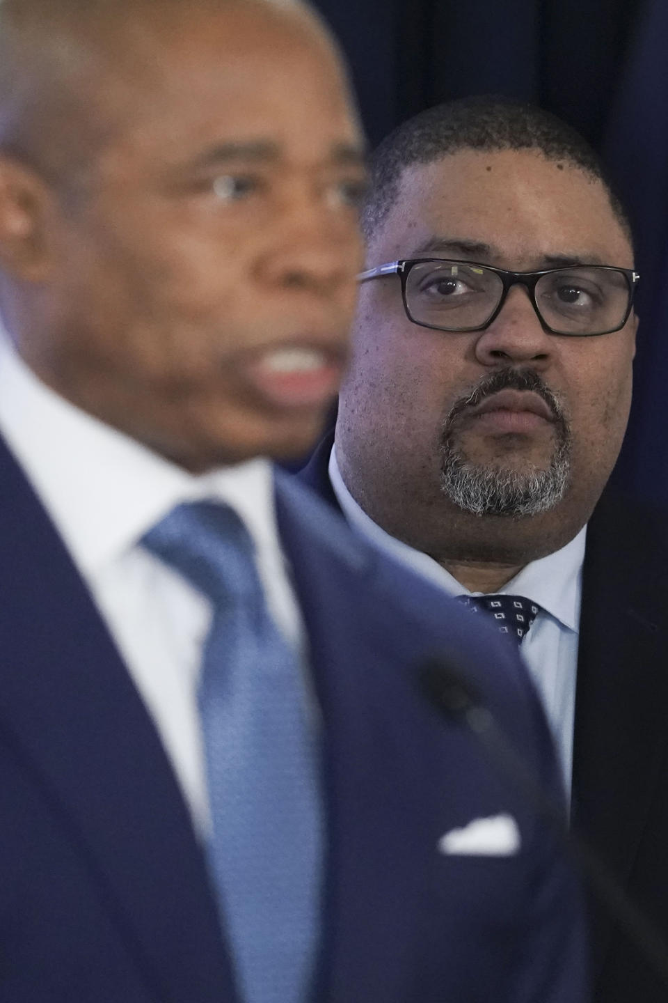 District Attorney Alvin Bragg, right, listens as Mayor Eric Adams, left, speak during a press conference where several charges for migrants involved in a Times Square brawl with police, Thursday, Feb. 8, 2024, in New York. (AP Photo/Bebeto Matthews)