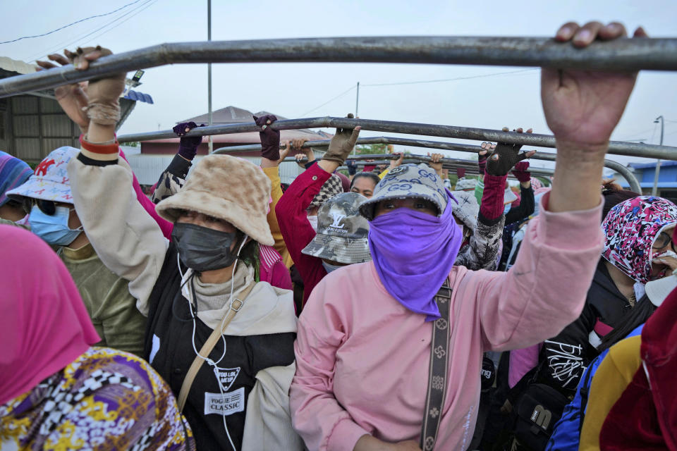 Cambodian garment workers stand on a back truck, wearing scarfs and caps to protect from the hot sun, after a day's work outside Phnom Penh Cambodia, Monday, April 29, 2024. (AP Photo/Heng Sinith)