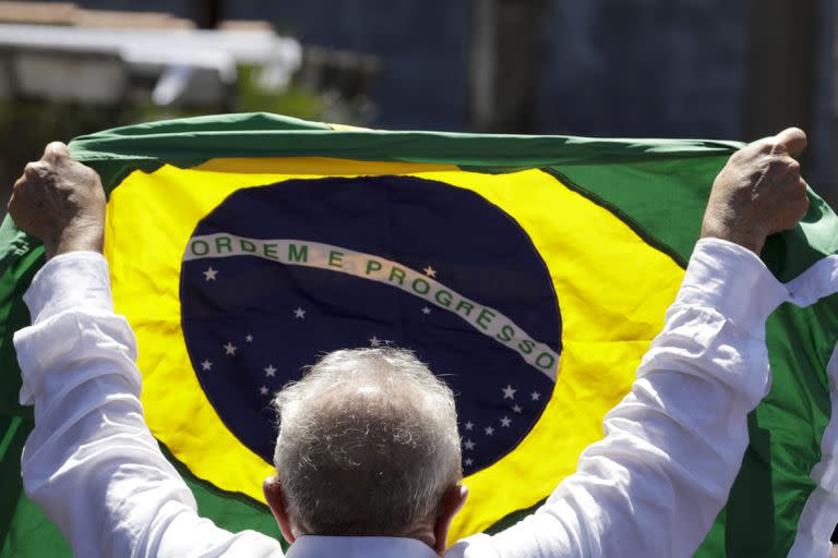 El expresidente brasileño Luiz Inácio Lula da Silva, quien vuelve a postularse para presidente, sostiene una bandera brasileña después de votar en la segunda vuelta de las elecciones presidenciales en Sao Paulo, Brasil, el domingo 30 de octubre de 2022.