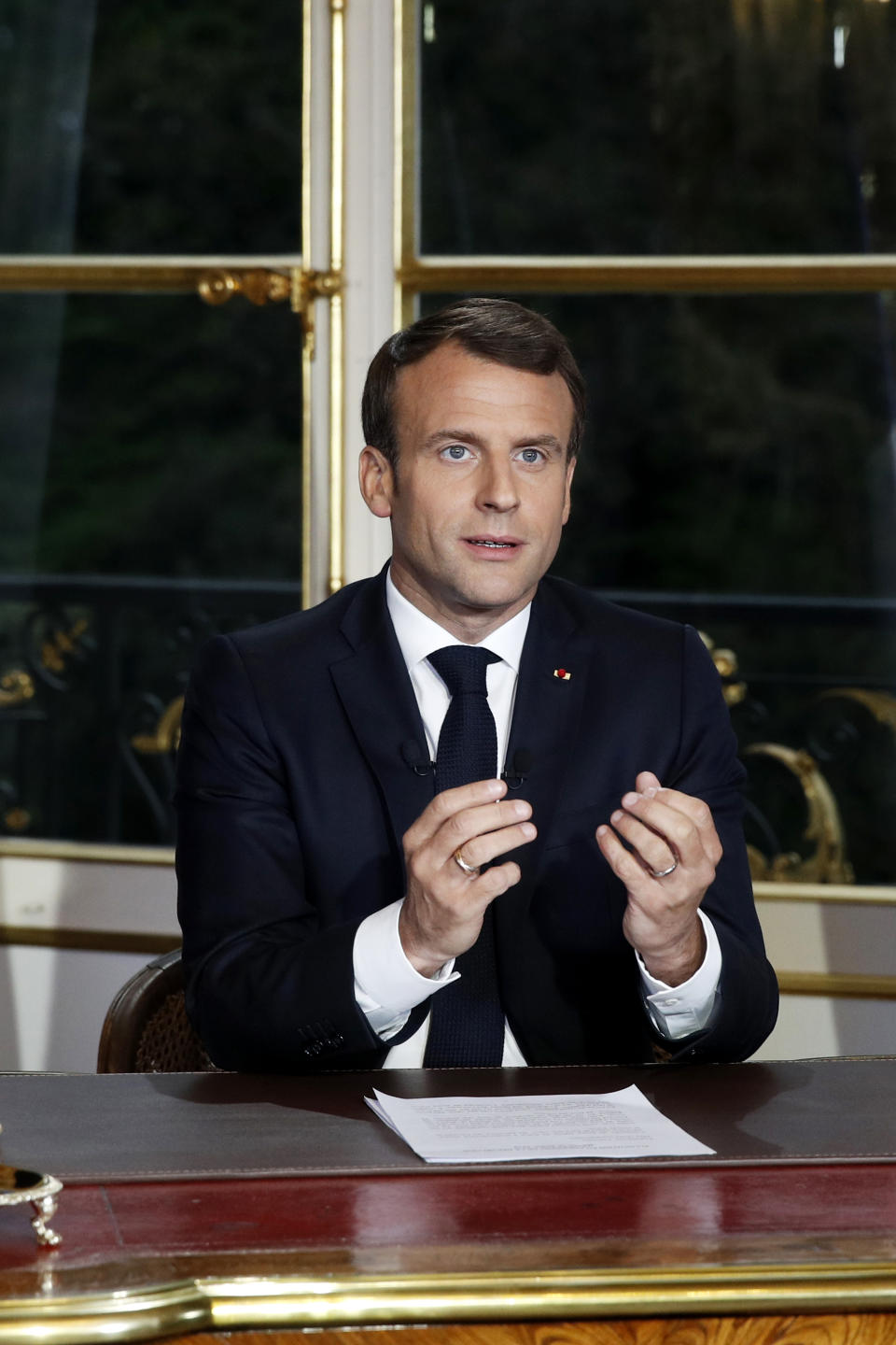 French President Emmanuel Macron gestures at his desk after addressing the French nation following a massive fire at Notre Dame Cathedral, at Elysee Palace in Paris, Tuesday, April 16 2019. Macron said he wants to see the fire-ravaged Notre Dame cathedral to be rebuilt within five years. (Yoan Valat, Pool via AP)