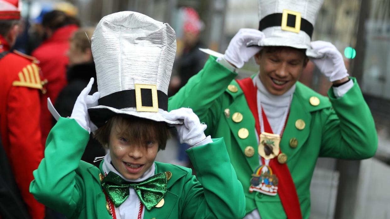 Kölner Karnevalisten halten im Wind ihre Kostüme fest.