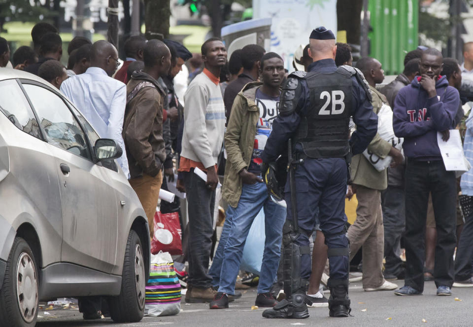 Police officer guards a group of migrants