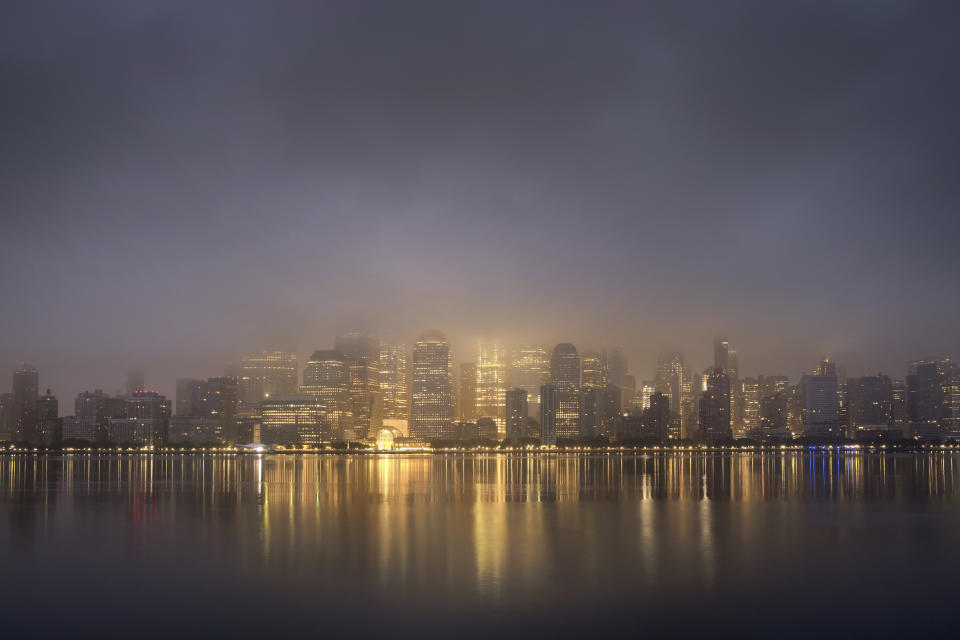 The lights of lower Manhattan burn through the low hanging clouds before sunrise on an overcast morning in New York City, Wednesday, June 19, 2019. (AP Photo/J. David Ake)