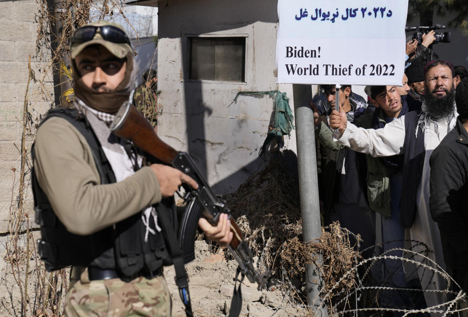 FILE - A Taliban fighter stand guards in front of protesters condemning President Joe Biden's decision on frozen Afghan assets in Kabul, Afghanistan, Feb. 15, 2022. After winding down 20 years of "endless" war in which the vast majority of Americans felt little impact on their daily lives, President Joe Biden now finds the U.S. mired in a conflict in Ukraine -- albeit without any U.S. troops on the ground -- that could prove to have more far-reaching effects on American lives than Iraq or Afghanistan ever did. (AP Photo/Hussein Malla, File)