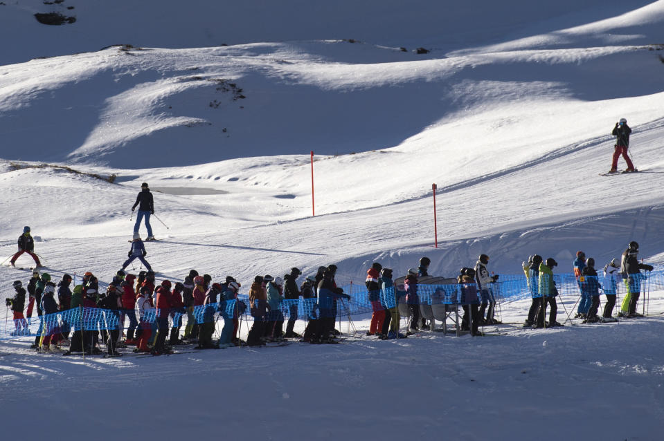 FILE - In this Sunday, Nov. 29, 2020 file photo ski enthusiasts with protective face masks queue for the ski lift, in Arosa, Switzerland. Swiss ski stations that has become an epicenter of discord among Alpine neighbors. EU member states Austria, France, Germany and Italy are shutting or severely restricting access to the slopes this holiday season amid COVID-19 concerns, Switzerland is not. (Gian Ehrenzeller/Keystone via AP, File)