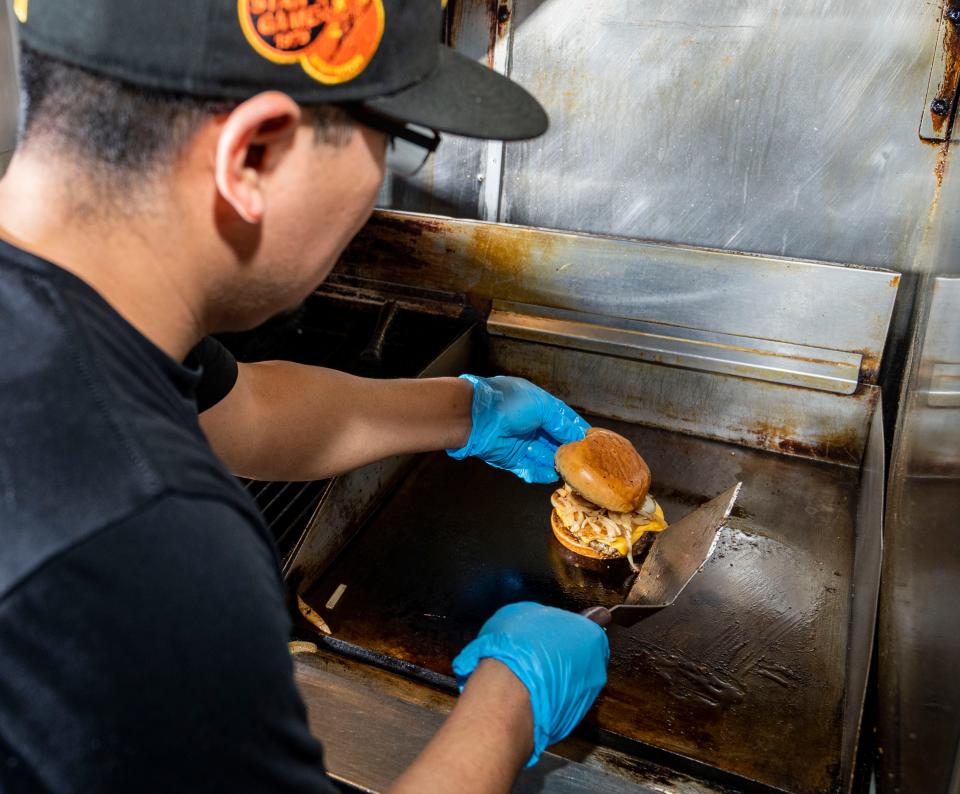 Alfredo Montero prepares The Burger, a half-pound Wisconsin beef patty with two slices of American cheese and grilled onions on a brioche bun, at Camino in Milwaukee's Walker's Point neighborhood.