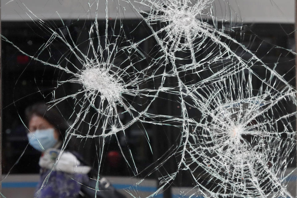 A woman wearing a mask due to coronavirus concerns, looks at a smashed storefront window in Boston's Downtown Crossing, Monday, June1, 2020. A march in Boston Sunday to protest the death of George Floyd, who died after being restrained by Minneapolis police officers on May 25, turned violent after dark. (AP Photo/Elise Amendola)