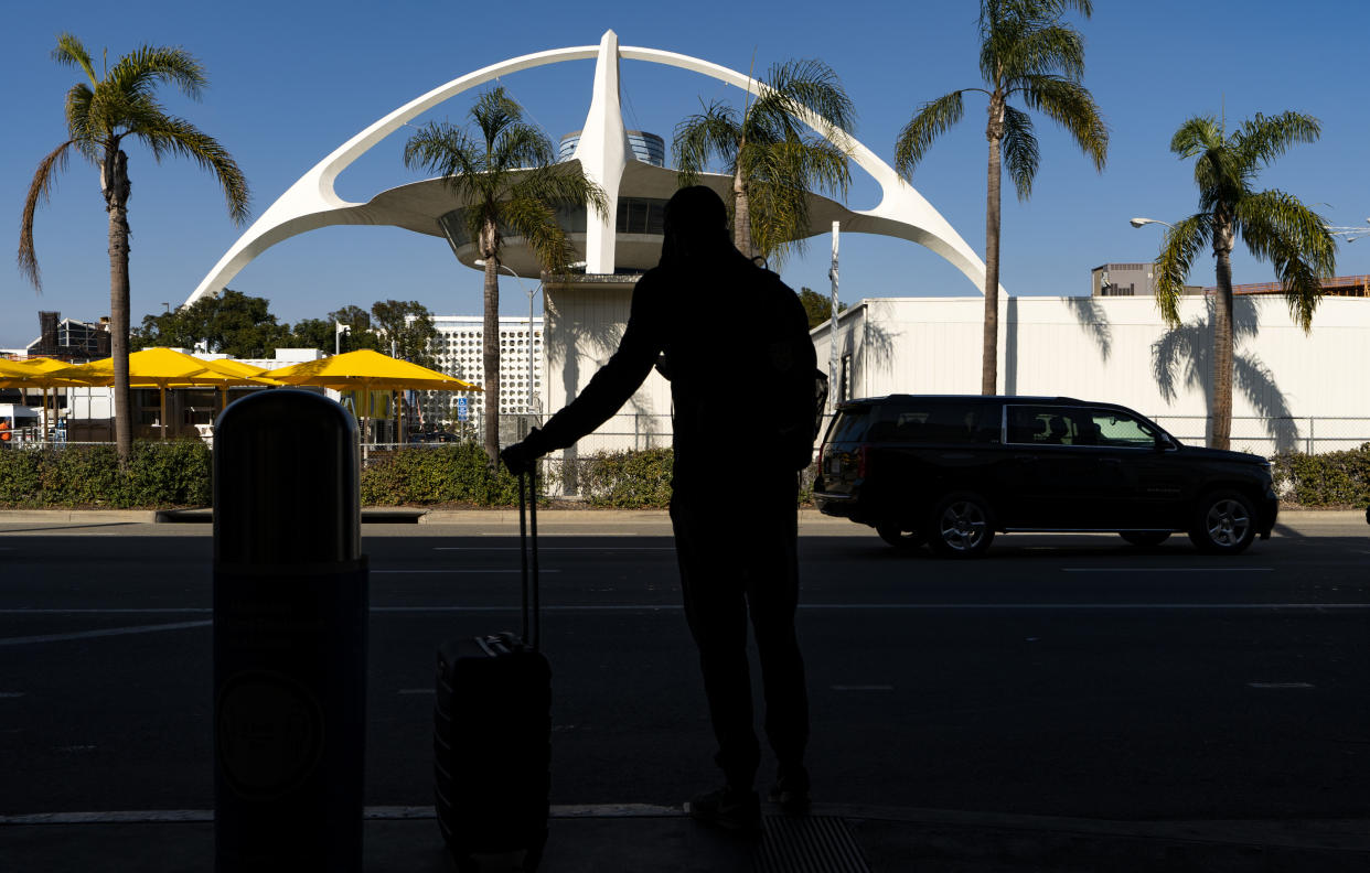 FILE - In this Nov. 25, 2020, file photo, a traveler awaits for transportation at the Los Angeles International Airport in Los Angeles. Airport police are investigating a driver who drove through a fence and onto the airfield. The intrusion Thursday, June 24, 2021, forced a sudden closure of some runways. (AP Photo/Damian Dovarganes, File)