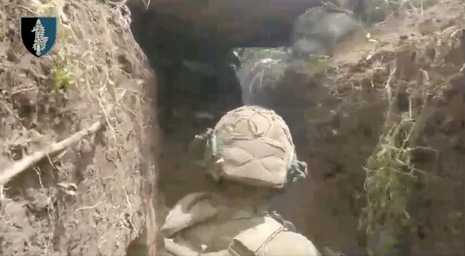 A Ukrainian soldier breaches a Russian trench.