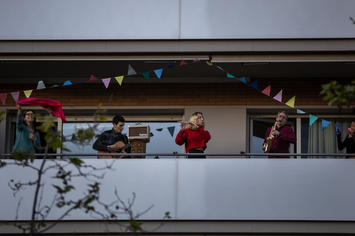 Family members play their instruments performing the song "Aleluya" on their balcony in support of the medical staff that are working on the COVID-19 virus outbreak in Barcelona, Spain, Sunday, April 5, 2020. Spanish Prime Minister Pedro Sanchez announced that he would ask the Parliament to extend the state of emergency by two more weeks, taking the lockdown on mobility until April 26. The new coronavirus causes mild or moderate symptoms for most people, but for some, especially older adults and people with existing health problems, it can cause more severe illness or death. (AP Photo/Emilio Morenatti)