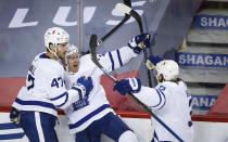 Toronto Maple Leafs' Travis Boyd, center, celebrates his goal with teammates Pierre Engvall, left, and Justin Holl during the second period of an NHL hockey game against the Calgary Flames, Tuesday, Jan. 26, 2021 in Calgary, Alberta. (Jeff McIntosh/The Canadian Press via AP)