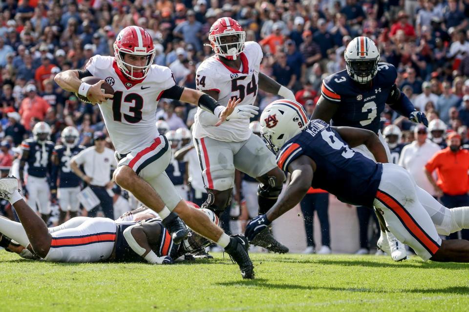 Georgia quarterback Stetson Bennett (13) carries the ball as he tries to get past Auburn linebacker Zakoby McClain (9) during the first half at Jordan-Hare Stadium.