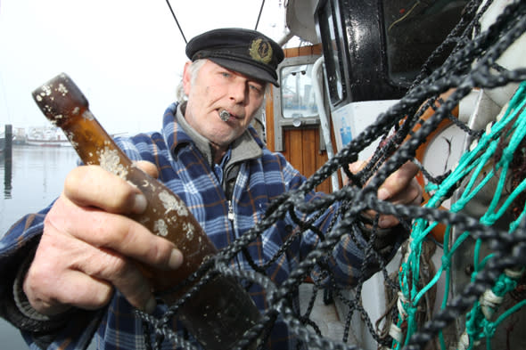 Fisher Konrad Fischer holds a message in a bottle from 1913 on the fishing cutter 