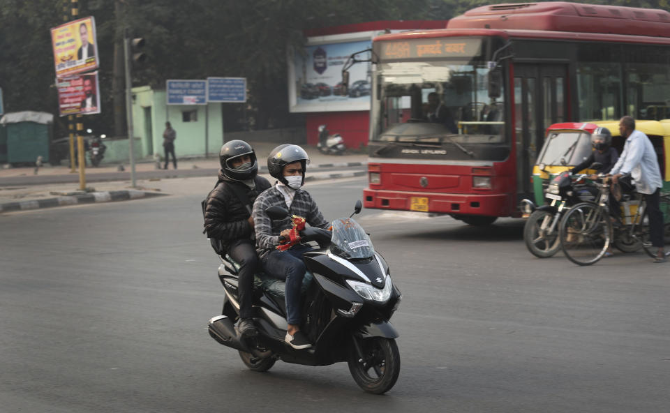 Scooterists ride with wearing a pollution mask a day after Diwali festival, in New Delhi, India, Thursday, Nov. 8, 2018. Toxic smog shrouds the Indian capital as air quality falls to hazardous levels with tens of thousands of people setting off massive firecrackers to celebrate the major Hindu festival of Diwali on Wednesday night. (AP Photo/Manish Swarup)