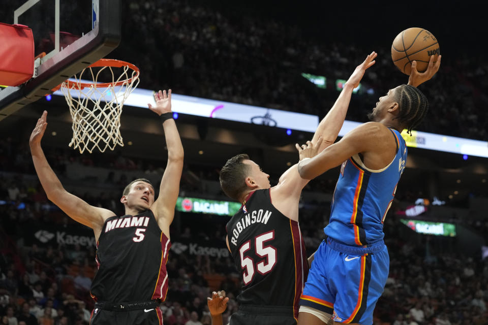 Oklahoma City Thunder guard Aaron Wiggins (21) drives to the basket as Miami Heat forwards Duncan Robinson (55) and Nikola Jovic (5) defend during the first half of an NBA basketball game, Wednesday, Jan. 10, 2024, in Miami. (AP Photo/Marta Lavandier)