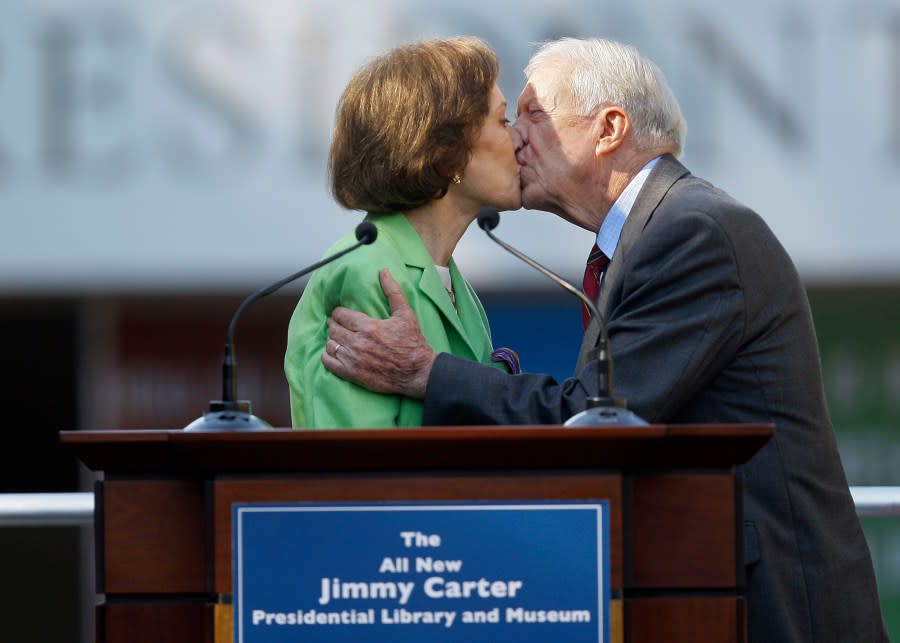 FILE – This Oct. 1, 2009 file photo shows former President Jimmy Carter getting a kiss from his wife Rosalynn as she introduces him during a reopening ceremony for the newly redesigned Carter Presidential Library in Atlanta. Jimmy Carter and his wife Rosalynn celebrate their 75th anniversary this week on Thursday, July 7, 2021. (AP Photo/John Bazemore, File)