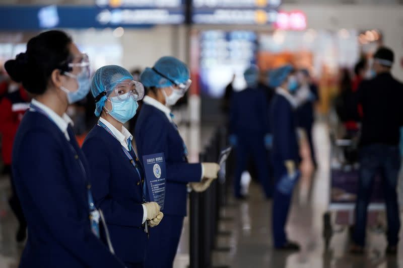 Staff member holds a sign with a QR code for travellers to indicate their health status at the Wuhan Tianhe International Airport