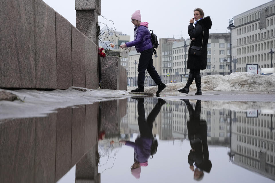 A woman lays flowers paying respect to Alexei Navalny at the Memorial to Victims of Political Repression in St. Petersburg, Russia, Saturday, Feb. 24, 2024. Navalny, 47, Russia's most well-known opposition politician, unexpectedly died on Feb. 16 in the penal colony, prompting hundreds of Russians across the country to stream to impromptu memorials with flowers and candles. (AP Photo/Dmitri Lovetsky)