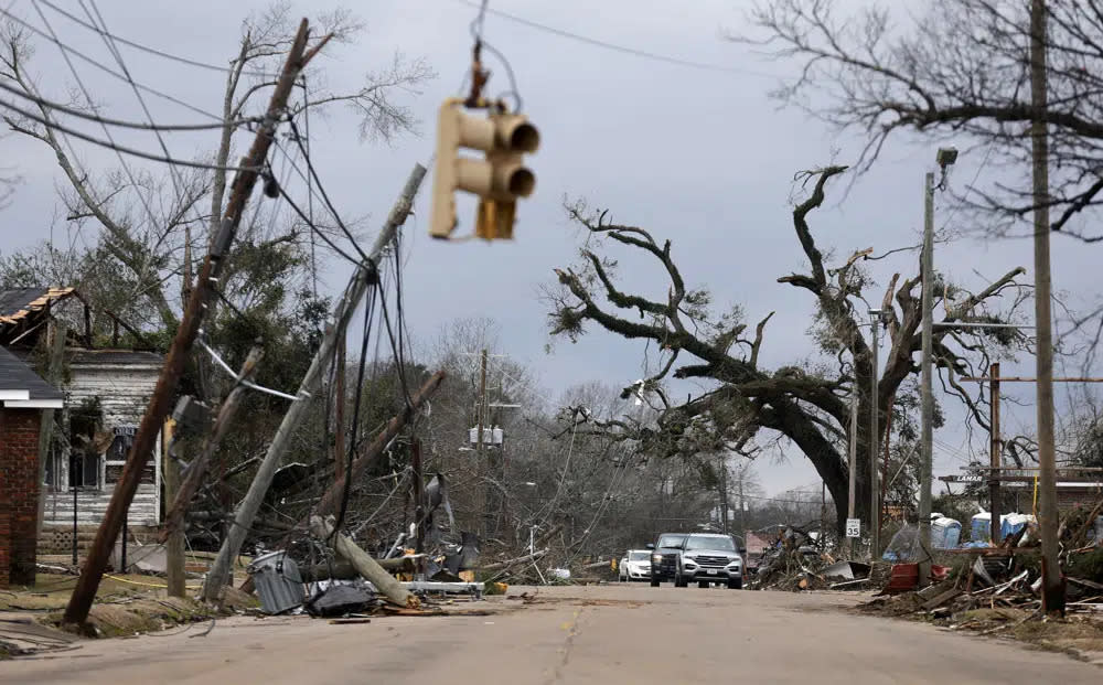 Cars carefully navigate downed trees and power lines on Chestnut Blvd. in Selma, Alab., Friday, Jan. 13, 2023, after a tornado passed through the area the day before. (AP Photo/Stew Milne)