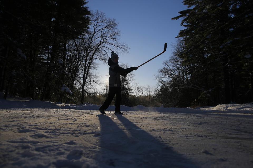 Connor Patterson plays hockey on a pond following a winter nor'easter snow storm in Boxford