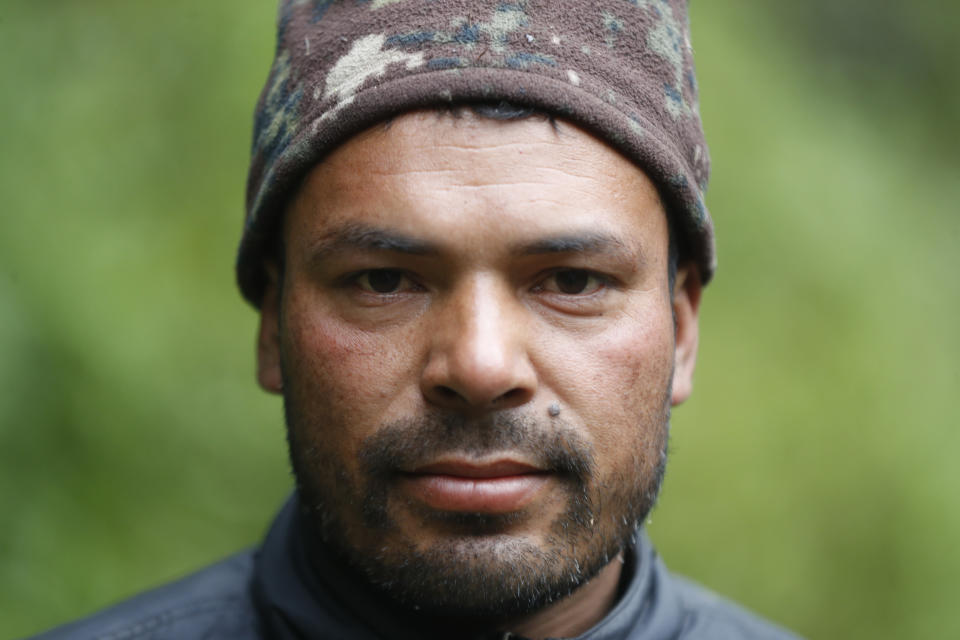 Nepalese honey hunter Devi Bahadur Nepali, poses for a photograph as he sets out for harvest with his team in Dolakha, 115 miles east of Kathmandu, Nepal, Nov. 20, 2021. High up in Nepal's mountains, groups of men risk their lives to harvest much-sought-after wild honey from hives on cliffs. (AP Photo/Niranjan Shrestha))