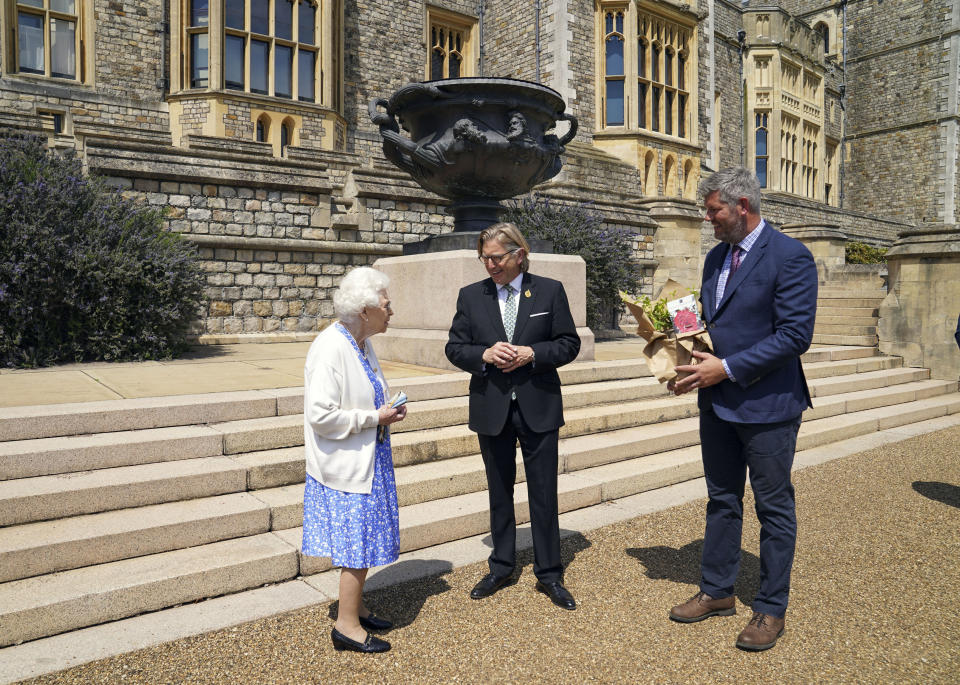 Britain's Queen Elizabeth II receives a Duke of Edinburgh rose, with Keith Weed, centre, President of the Royal Horticultural Society, at Windsor Castle, England, Wednesday June 9, 2021. The newly bred deep pink commemorative rose has officially been named in memory of the late Prince Philip Duke of Edinburgh. A royalty from the sale of each rose will go to The Duke of Edinburgh's Award Living Legacy Fund to support young people taking part in the Duke of Edinburgh Award scheme. (Steve Parsons/Pool via AP)