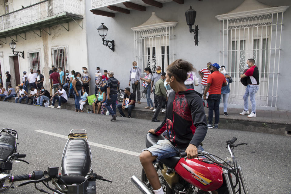 People wearing masks as a precaution against the spread of the new coronavirus, stand outside a polling place waiting to vote during the presidential elections, in Santo Domingo, Dominican Republic, Sunday, July 5, 2020. (AP Photo/Tatiana Fernandez)