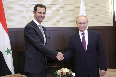 Russian President Vladimir Putin (R) shakes hands with Syrian President Bashar al-Assad during a meeting in the Black Sea resort of Sochi, Russia November 20, 2017. Sputnik/Mikhail Klimentyev/Kremlin via REUTERS