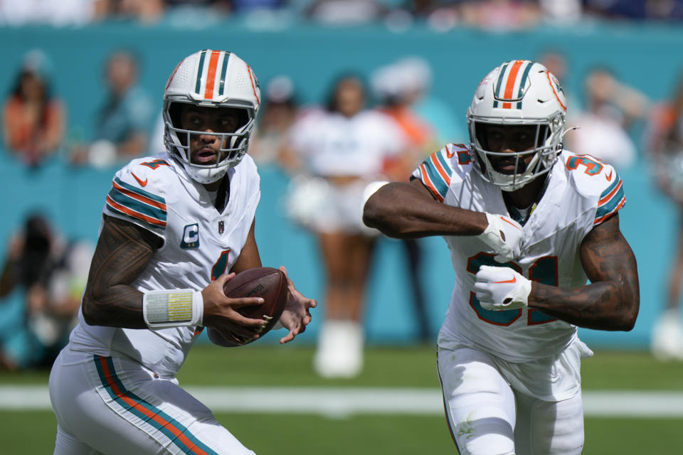 Miami Dolphins quarterback Tua Tagovailoa (1) looks to make a play as Miami Dolphins running back Raheem Mostert (31) fakes a handoff during the first half of an NFL football game against the New England Patriots, Sunday, Oct. 29, 2023, in Miami Gardens, Fla. (AP Photo/Wilfredo Lee)