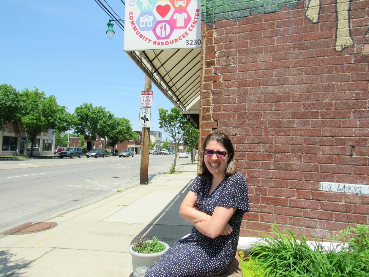 Stephanie Baker sits on a stone fence in front of the Clintonville-Beechwold Community Resources Center (and next to the CRC annex), 3222 N. High St. Baker was recently named senior director of the CRC after Bill Owens resigned April 18.