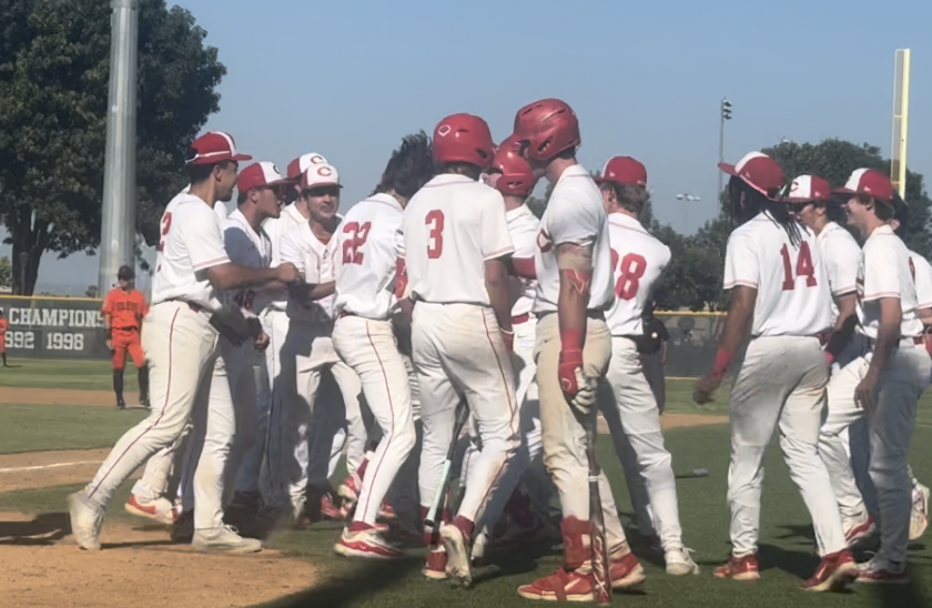 Corona players surround Seth Hernandez (22) after his two-run home run in the bottom of the sixth inning