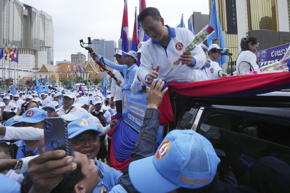 Cambodian People's Party's Hun Manet, upper, a son of Cambodia Prime Minister Hun Sen, greets supporters as he leads a procession to mark the end of its election campaign, in Phnom Penh, Cambodia, Friday, July 21, 2023. Hun Sen says he is ready to hand the premiership to his oldest son, Hun Manet, who heads the country's army. (AP Photo/Heng Sinith)