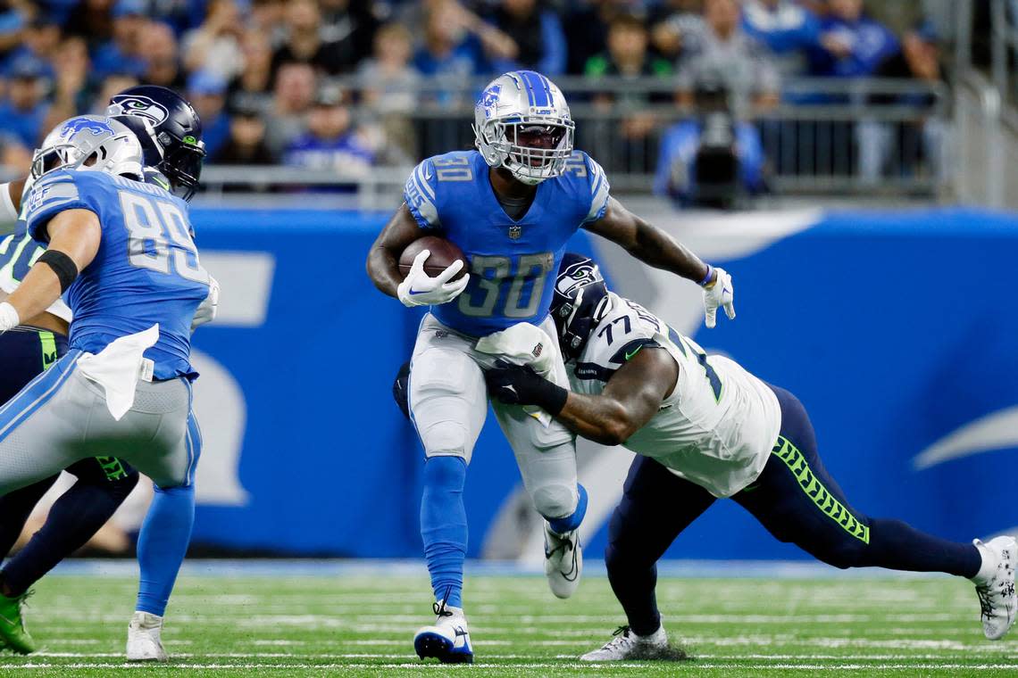 Detroit Lions running back Jamaal Williams (30) is tackled by Seattle Seahawks defensive tackle Quinton Jefferson (77) during the first half of an NFL football game, Sunday, Oct. 2, 2022, in Detroit. (AP Photo/Duane Burleson)