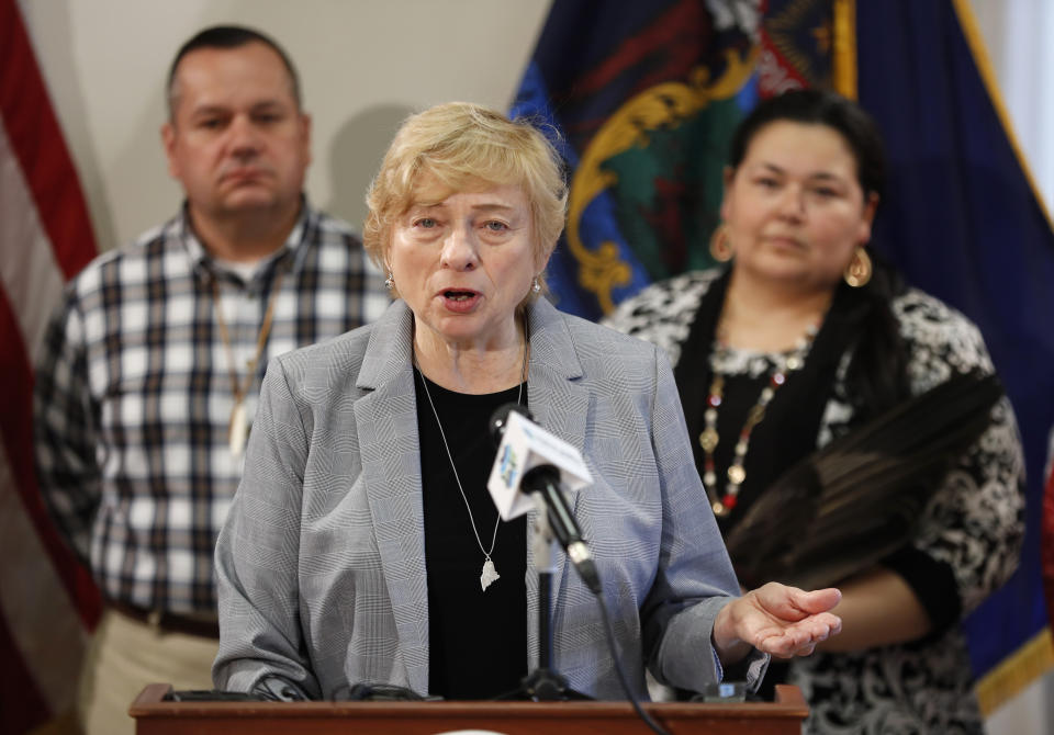 Maine Gov. Janet Mills speaks at the signing ceremony to establish Indigenous Peoples' Day, Friday, April 26, 2019, at the State House in Augusta, Maine. Mills added Maine to the growing number of states who have passed similar legislation. William J. Nicholas Sr., Governor of the Passamaquoddy Tribe-Indian Township, left, and Clarissa Sabattus, Tribal Chief of Houlton Band of Maliseet Indians attend the event. (AP Photo/Robert F. Bukaty)