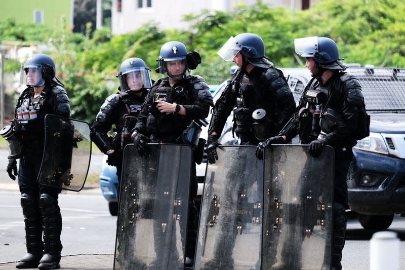 French police stand with their shields at the entrance of the Vallee-du-Tir district, in Noumea on May 14, 2024. - Photo: Theo Rouby / AFP (Getty Images)