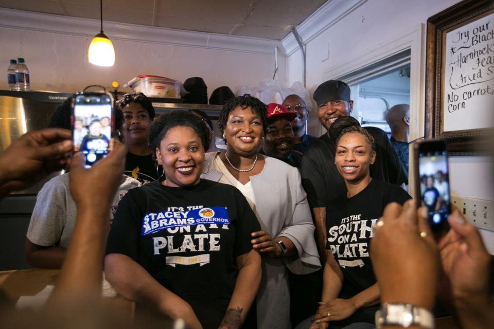 Abrams poses in a restaurant with other Black women, some wearing pro-Abrams gear