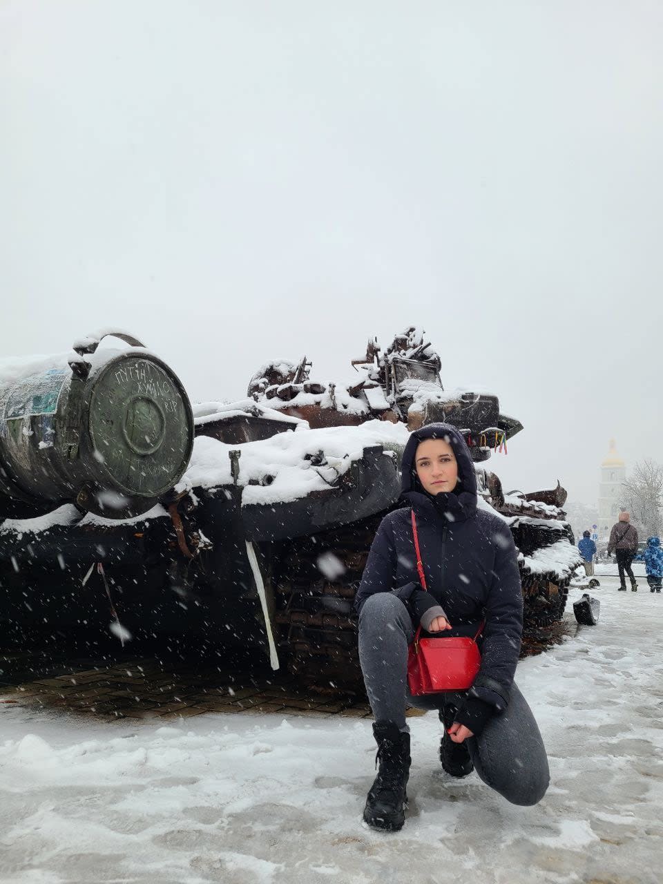 Sakhnatska kneeling by a destroyed Russian tank in central Kyiv when she returned to Ukraine the first time during the war, in November 2022.