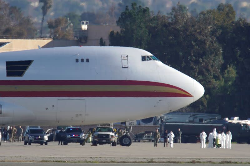 Personnel in protective clothing approach an aircraft at March Air Reserve Base in Riverside County