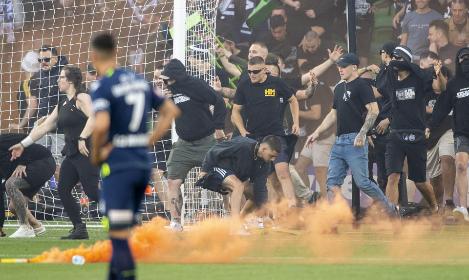 Melbourne Victory fans invade the pitch during the A-League Men's soccer match between Melbourne City and the Melbourne Victory at AAMI Park in Melbourne, Australia Saturday, Dec. 17, 2022. The soccer match between rivals Melbourne City and Melbourne Victory was abandoned Saturday after fans invaded the field and attacked City goalkeeper Tom Glover.(Will Murray/AAP Image via AP)