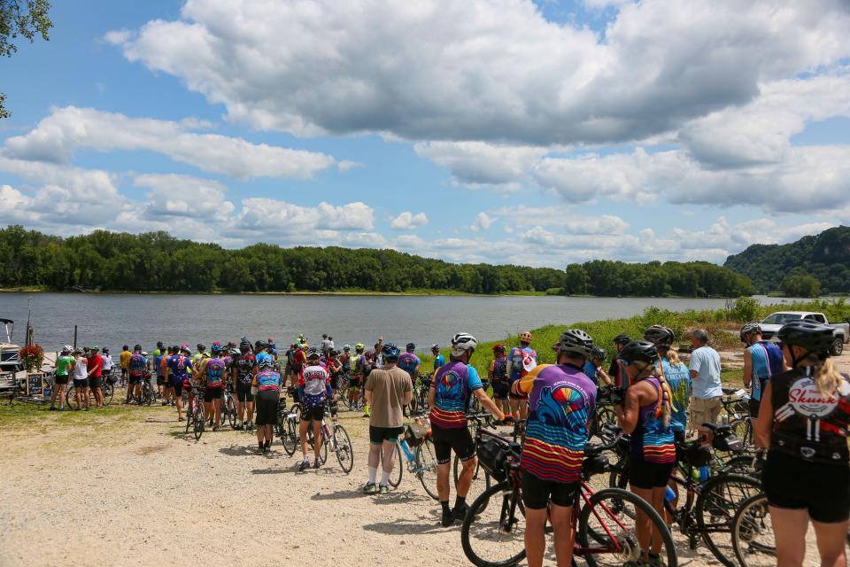 Riders line up to dip their bike tires in the Mississippi at Lansing on the last day of RAGBRAI July 30, 2022.