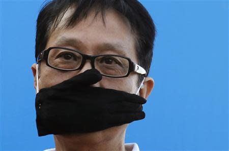 A protester covers his mouth with a glove during a demonstration demanding freedom of speech and press freedom in Hong Kong February 23, 2014. REUTERS/Bobby Yip