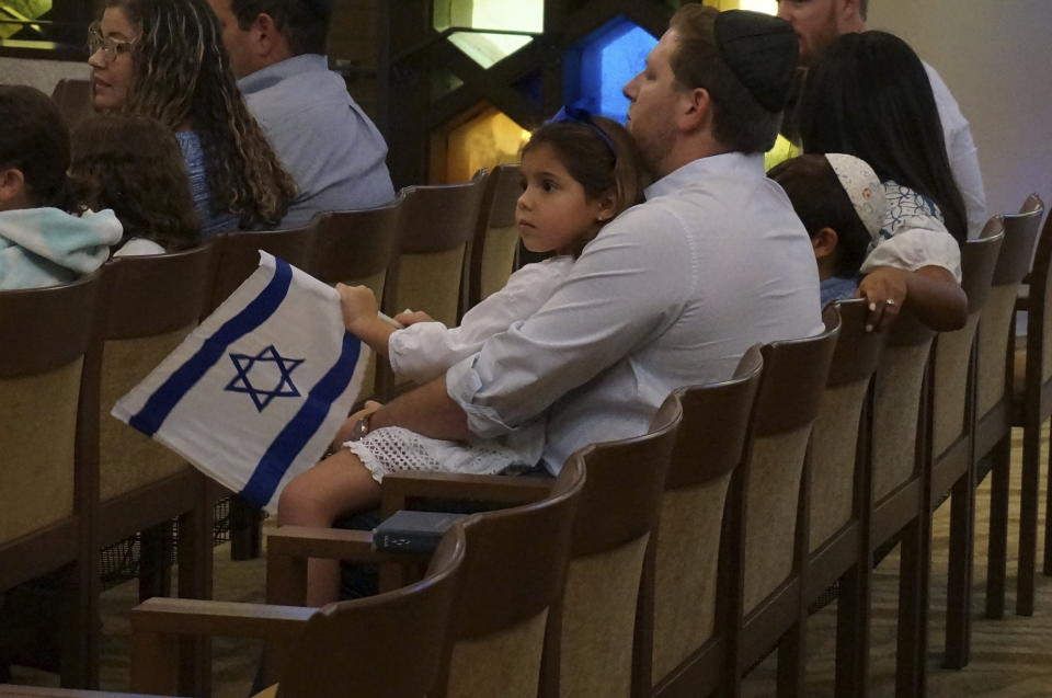 A family with Israel flags attends Shabbat services at Temple Beth Sholom in Miami Beach, Fla., on Friday, Oct. 13, 2023. Tears flowed as the rabbis led about 300 congregants in praying for peace, for safety for the people of Israel and the soldiers defending it, and especially for the hostages taken in Hamas's brutal attack. (AP Photo/Giovanna Dell'Orto)