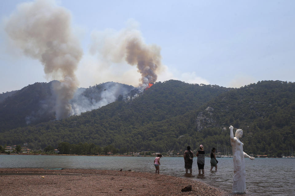 People watch a wildfire burning the forest in Turgut village, near tourist resort of Marmaris, Mugla, Turkey, Wednesday, Aug. 4, 2021. As Turkish fire crews pressed ahead Tuesday with their weeklong battle against blazes tearing through forests and villages on the country's southern coast, President Recep Tayyip Erdogan's government faced increased criticism over its apparent poor response and inadequate preparedness for large-scale wildfires.(AP Photo/Emre Tazegul)