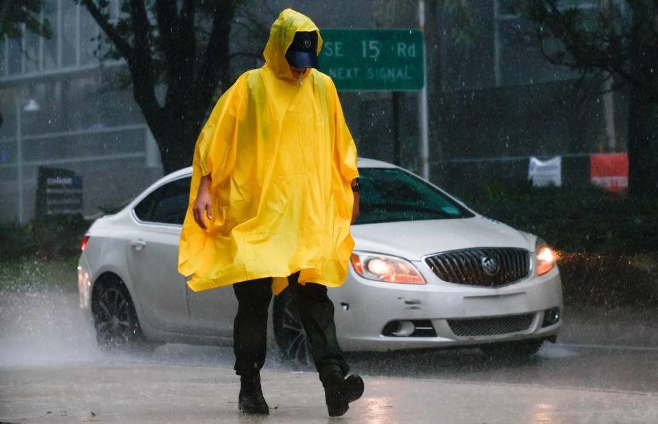 A poncho-wearing pedestrian smokes in the rain as he walks along the sidewalk off Brickell Avenue in Miami, Florida, on Tuesday, Sept. 27, 2022. This file photo was taken during a time of alert ahead of Hurricane Ian’s tropical storm-force winds. On March 29, 2023, the weather was not nearly as threatening but there were thunderstorms and reports of street flooding in parts of Miami-Dade and Broward.