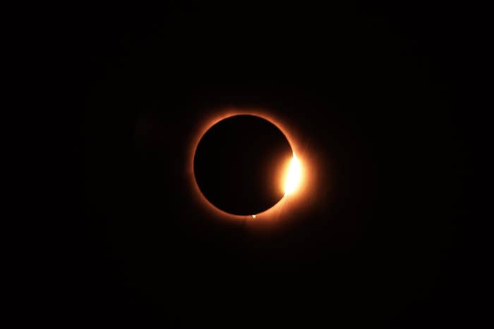 Solar eclipse with moon covering most of the sun, leaving a bright crescent visible